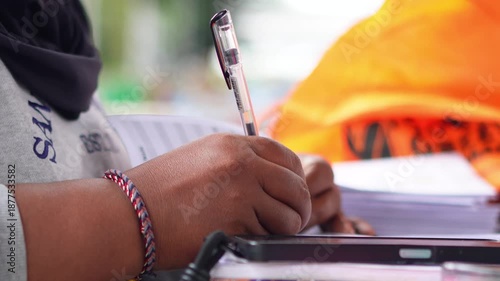 A person counting numbers and writing notes on paper, focused on calculation, planning, or financial work