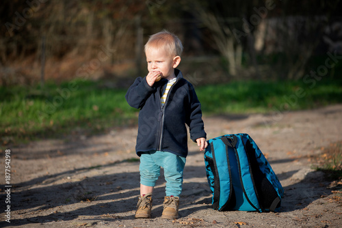 Curious Toddler Standing Outdoors with Backpack on Rural Path