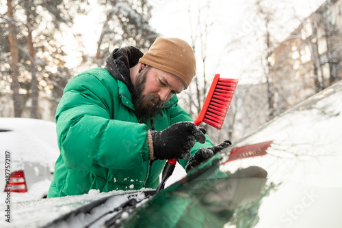 Man Scraping Ice from Cowl Area Under Car Wipers