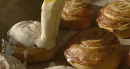 Homemade Cinnamon Pastries Covered with White Sugar Glaze on Baking Paper