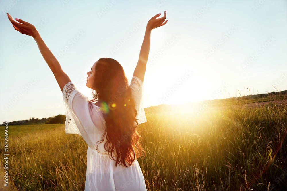 Fototapeta premium Vacation, back and woman at field for freedom on adventure, travel or summer holiday in countryside. Arms up, meadow and person in nature on getaway trip at sunset with flare, space and peace outdoor