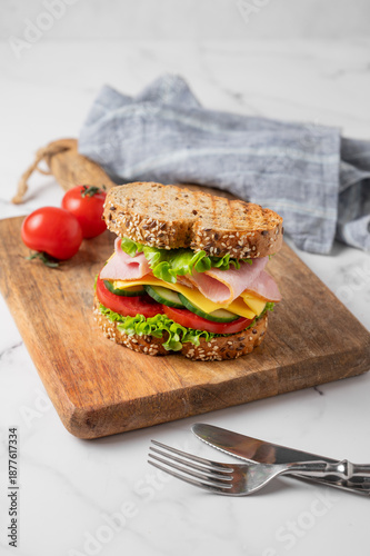 Canvastavla Sandwich with ham, cheese, lettuce, vegetables and seeded bread on a wooden boar
