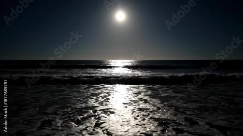 A serene seascape featuring the bright sun reflecting on dark waves and the ocean. Waves crashing near shore with glowing reflections