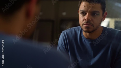 Serious man Staring at Himself in the Mirror at Night
