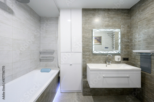 Картината върху платно modern bathroom with grey textured tiles, white floating sink, tall white storag