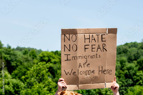 Bild auf Leinwand A protestor at a political rally holds a sign that reads no hate, no fear, immigrants are welcome here, advocating for immigrant rights, acceptance and community inclusion