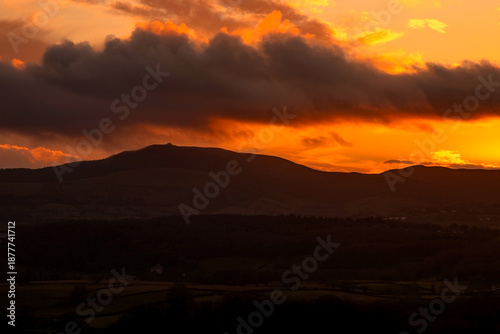 Cloudy dark sunset, silhouetting mountains, woods and hills; featuring Moel Famau. Clwydian Hills, Clwyd, Wales