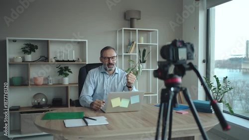 Middle Aged Businessman Recording Vlog in Office with camera
