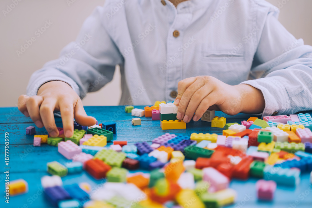 Naklejka premium Child playing and building with colorful toy bricks, plastic blocks.