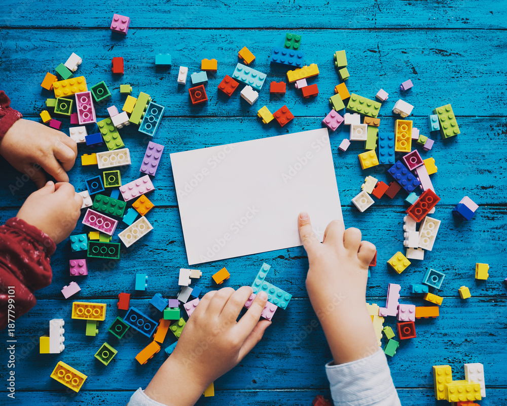 Fototapeta premium Child hands playing with colored toy bricks.