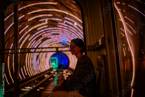 Woman seated inside a tunnel with colorful lights and circular patterns around her. Shanghai, China