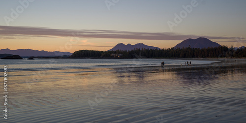 Scenic sunset beach view with silhouetted mountains and calm water reflections. Ucluelet, British Columbia, Canada
