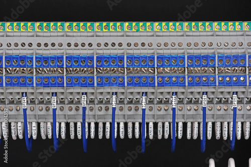 Electrical terminals with connected insulated wires with metal lugs. It is installed on a metal mounting rod in the electrical panel. 