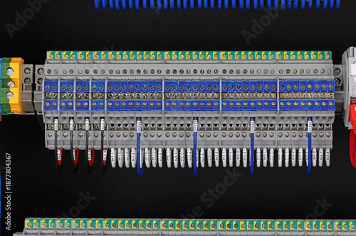 Electrical terminals with connected insulated wires with metal lugs. It is installed on a metal mounting rod in the electrical panel. 