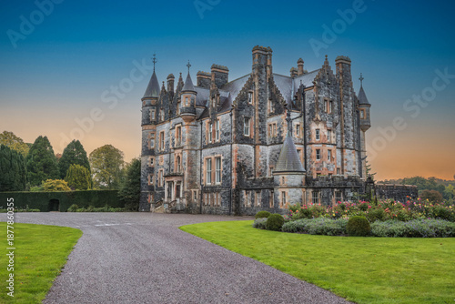 The exterior of Blarney house, built in a Scottish baronial style, in Cork, Ireland, captured in autumn under a moody sunset sky