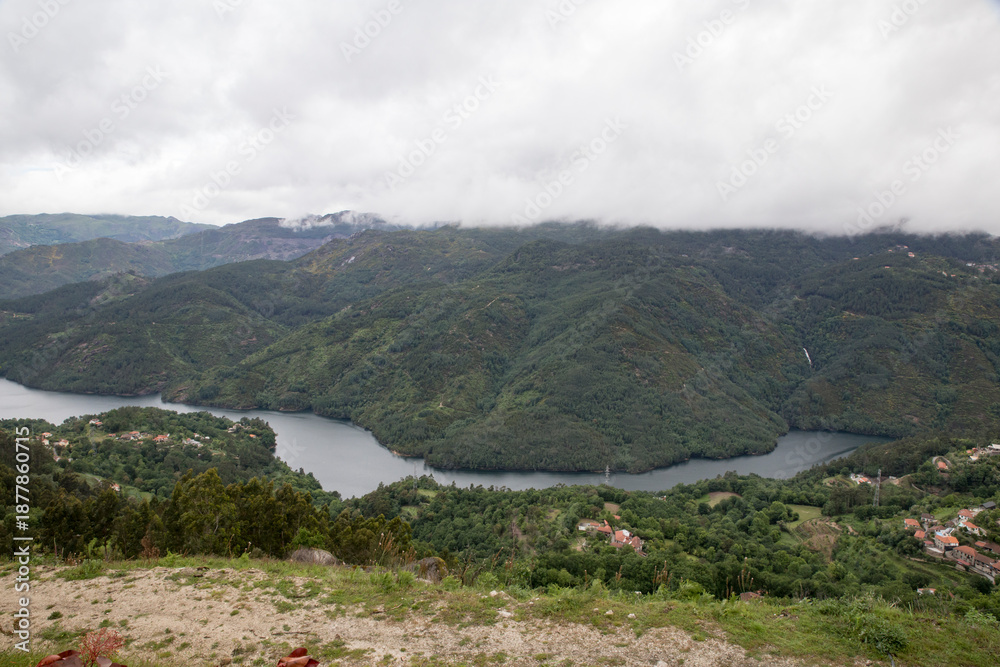 Obraz premium Paisagem montanhosa com rio serpenteante e cascata ao fundo.