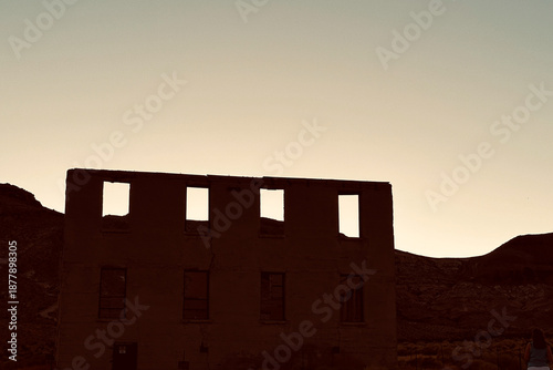Tableau sur toile Abandoned Building Silhouette in Desert Landscape at Dusk .