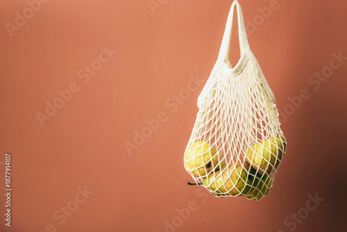 Fresh pears in hanging string bag against a brown backdrop. Zero waste concept. Copy space