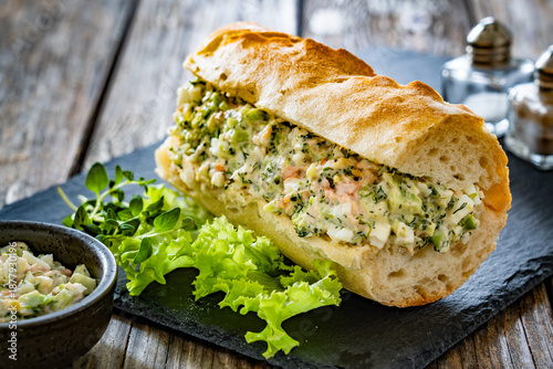 Foto Crispy baguette with egg salmon avocado paste on wooden table