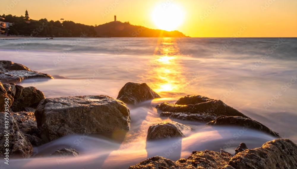 Obraz premium Golden hour at the beach with rocks and blurred waves.