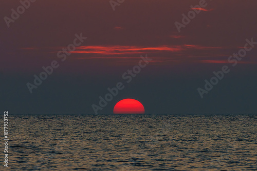 Sunset sunrise over the ocean, a setting sun rising over the sea, red.