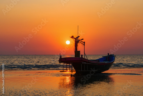 The sun begins to set and the silhouette of a fishing boat.