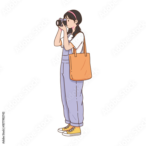 Young female photographer in purple overalls taking pictures with professional camera and carrying a canvas tote bag on white background