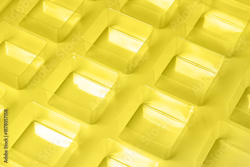 An industrial transparent square thermoforming mold made of plastic as a packaging solution for industrial products. Foil cubes on a white background and shining lights.
