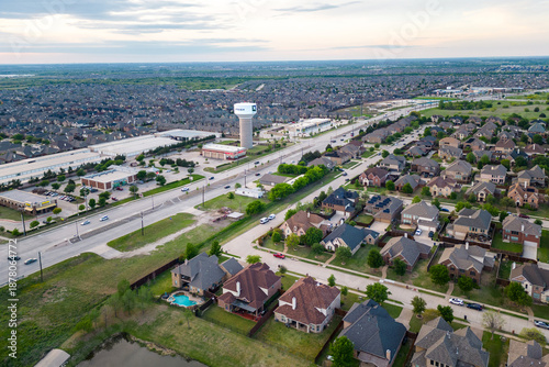 Aerial view of suburban neighborhood with houses roads commercial buildings and water tower