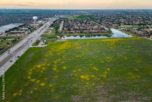 Aerial view of suburban landscape with open field lake residential houses and connecting roads