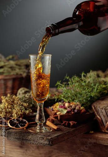 Fotografía Herbal bitter liqueur is poured from a vintage bottle into a glass