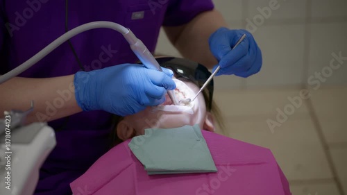 During a dental appointment, a skilled dentist carefully cleans a childs teeth in slow motion. The bright clinic provides a calming atmosphere for the little patient.