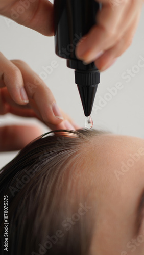 Woman applying hair serum to her scalp for healthy hair growth and nourishment