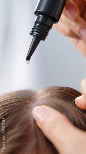 Woman applying hair serum to her scalp for healthy hair growth and nourishment