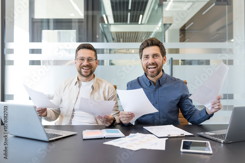 Foto Two male business partners celebrating a successful project, smiling and holding