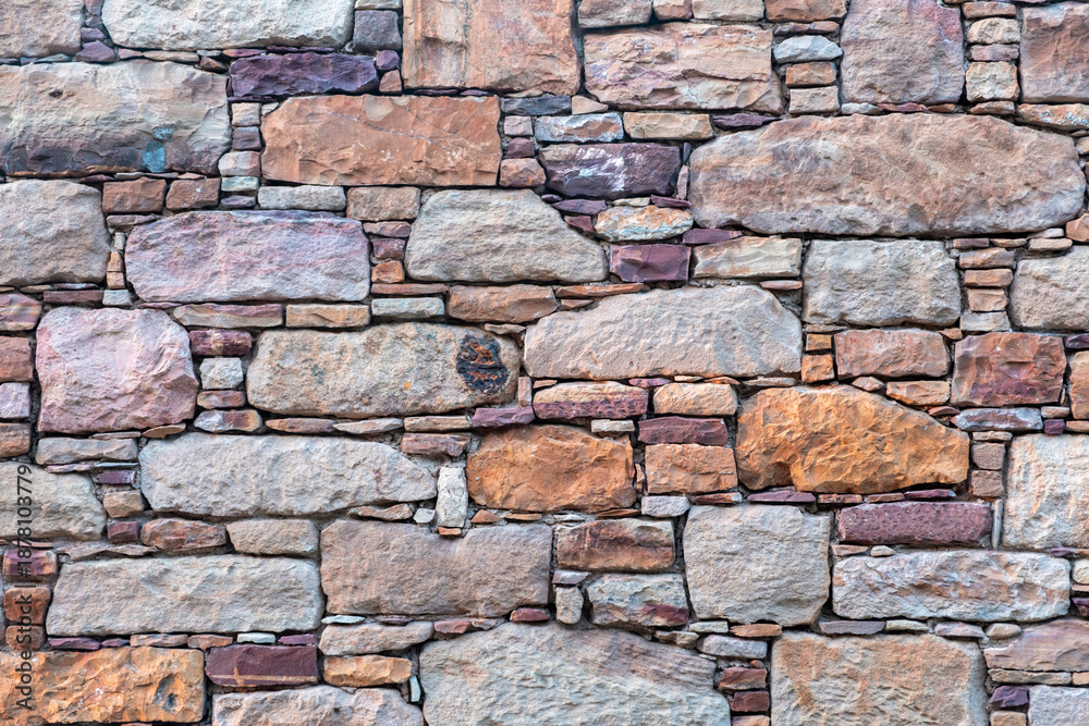 Fototapeta premium Traditional Kampos stone wall background, Chios Island, Greece. Rectangular blocks in warm red brown colors.