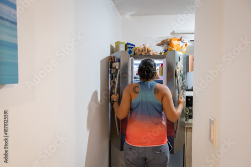 Фотография Woman looks at refrigerator full of fattening food