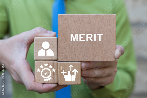 фотографія Business person holding wooden blocks sees the text MERIT