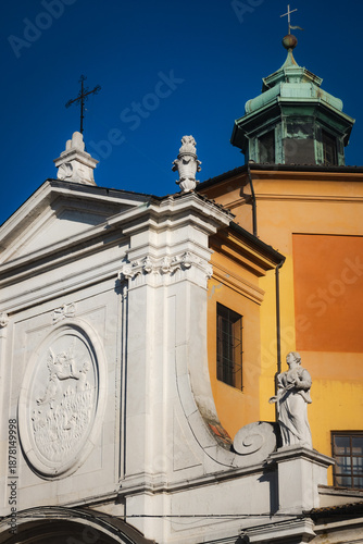 Facade of the Church of Santa Maria del Suffragio in Piazza del Popolo, Ravenna, Italy. Featuring Baroque white marble details and an adjacent orange-yellow wall with a green dome.