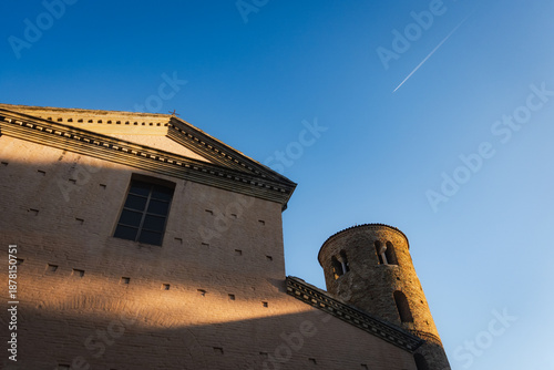 Exterior view of the Basilica di Santa Maria Maggiore in Ravenna, Italy, featuring a simple brick facade and an adjacent historic cylindrical bell tower.