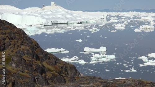 GREENLAND - 11.4.2025 - Great aerial timelapse of ice floes moving past a rock formation on Greenland's Disko Bay.