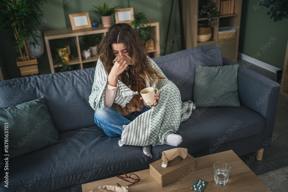 Obraz premium Woman with cold blowing nose holding warm drink at home