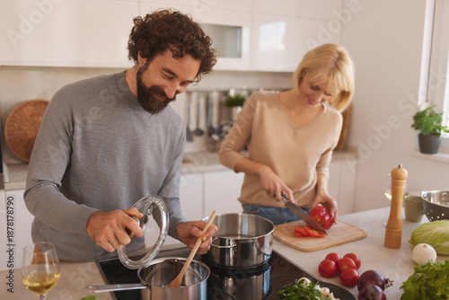 Photos Two people work together in a bright, contemporary kitchen, chopping vegetables and stirring pots to create a delicious meal, enjoying the process of cooking side by side