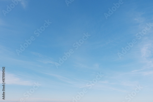 Blue sky with wispy clouds stretches over a calm horizon, presenting an expansive outdoor scene filled with serenity, light and natural air, ideal for nature, travel and minimalistic branding.