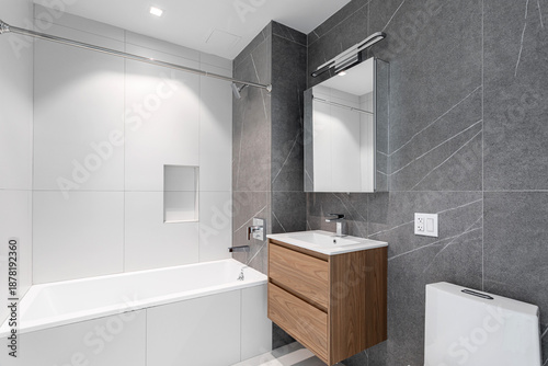 Schilderij op canvas Modern gray and white bathroom with built-in bathtub, floating wood vanity, and