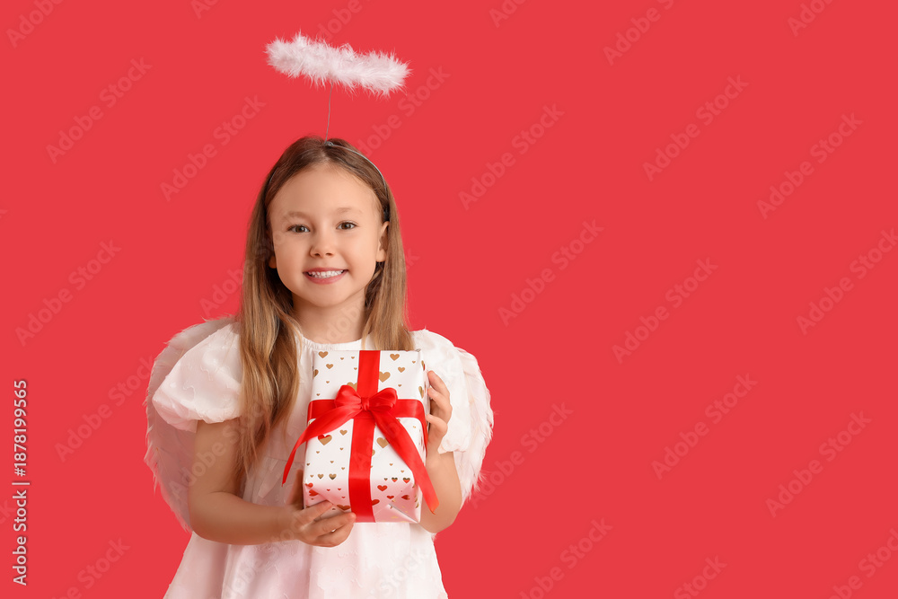 Fototapeta premium Cute little girl dressed as cupid with gift box on red background. Valentine's Day celebration