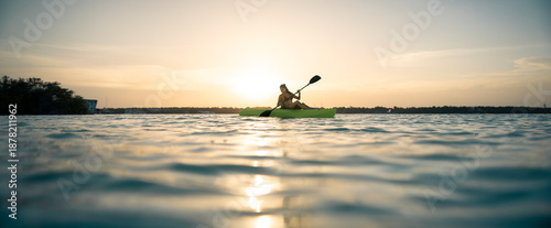 Fotografie Silueta a contraluz de una hermosa mujer joven latina navegando en kayak en el m