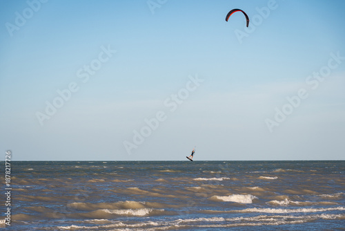 ide shot of an athletic woman kitesurfing in the sea.
