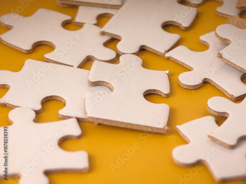 White jigsaw puzzle pieces scattered on an yellow background