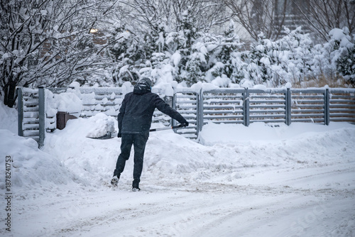 Człowiek odśnieżający drogę po intensywnych opadach śniegu.
